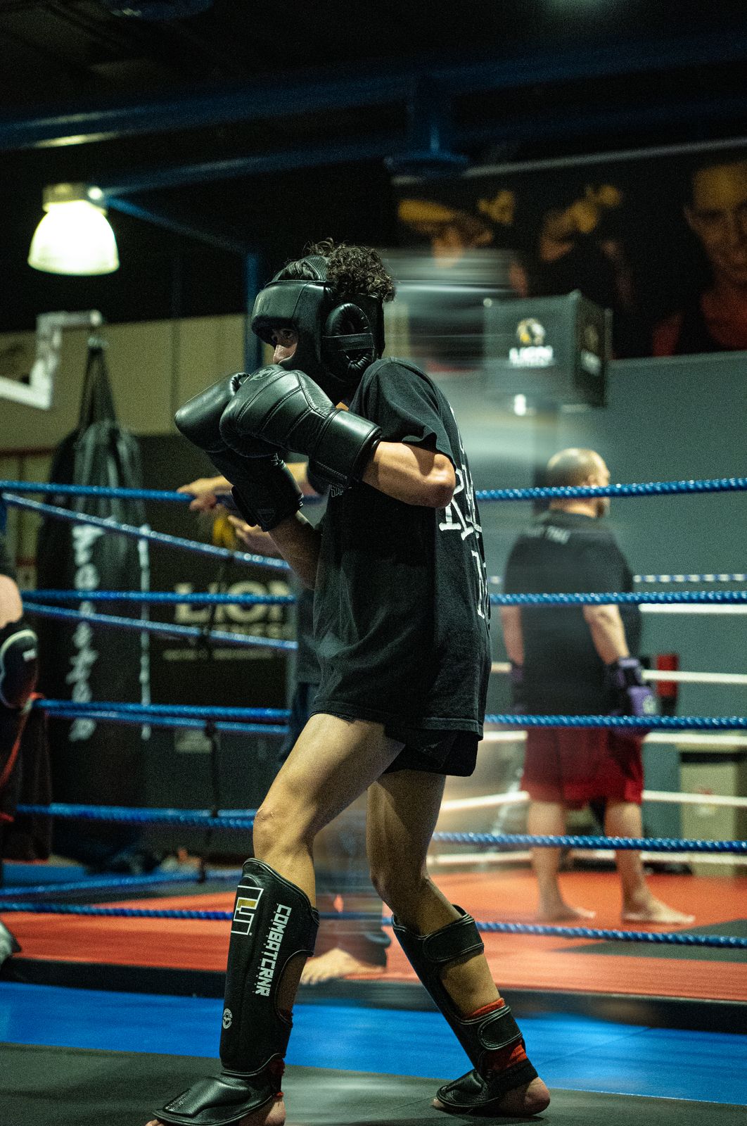 Fighter in headgear and shin guards shadow boxing in the ring