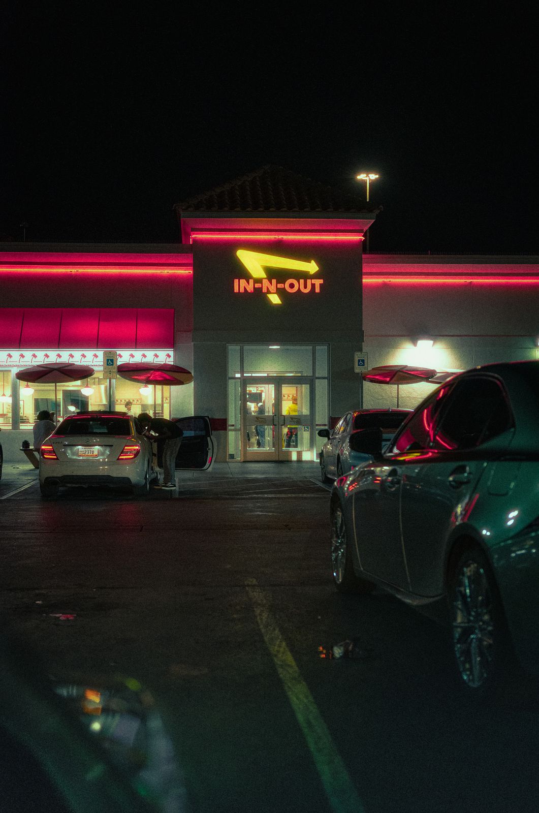 In-N-Out glowing red at night with cars in the parking lot