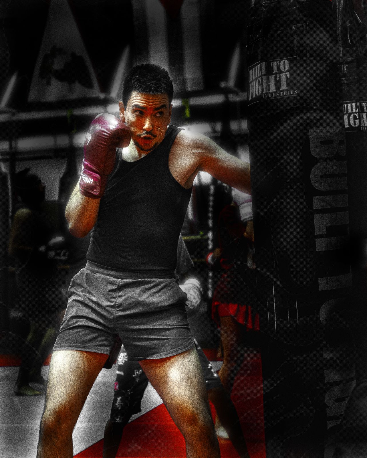 Boxer in guard stance next to a heavy bag, black and white with red gloves