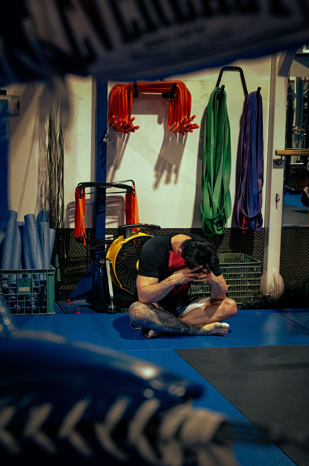 Fighter sitting on the gym floor between rounds with head in hands